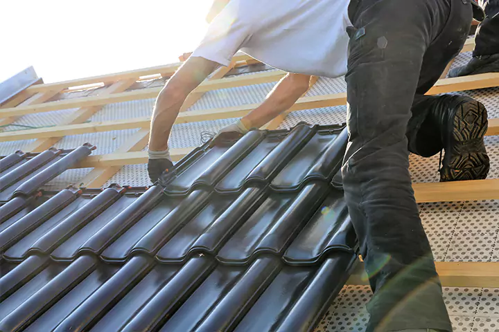 Dachdecker deckt ein Dach mit schwarzen Ziegeln neu ein