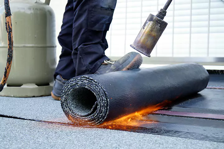 Dachdecker montiert Flachdachabdichtung aus Bitumen
